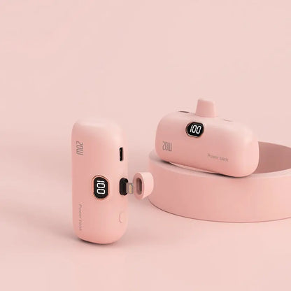 Pink mini fast charge power bank with Apple cable, wireless capsule design, compact portable power source on a matching background